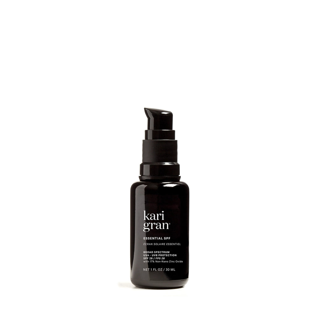 A bottle of kari gran essential spf face sunscreen on a white background.