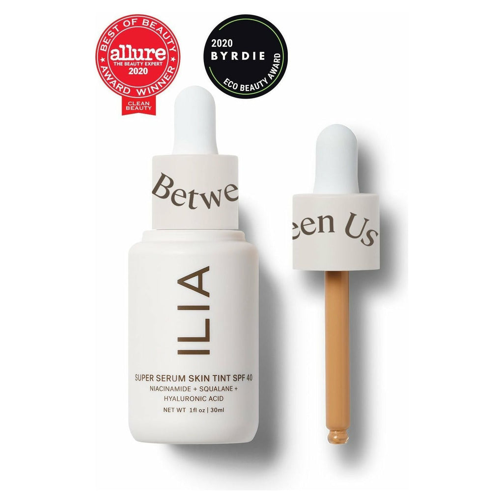 A dropper bottle of ilia super serum skin tint with a detached dropper next to it, indicating a skincare product with niacinamide, squalane, and hyaluronic acid.