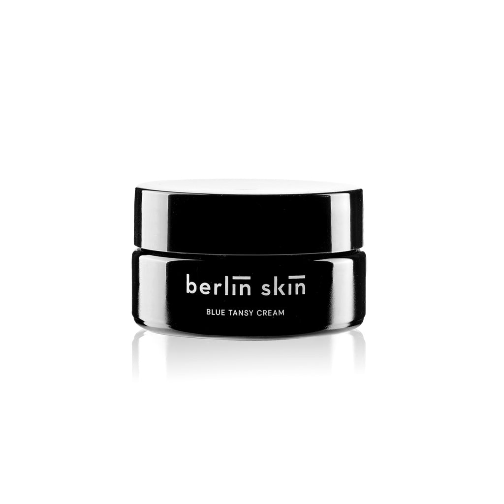 Black and white cosmetic jar labeled "berlin skin blue tansy cream" with a reflection on white background.