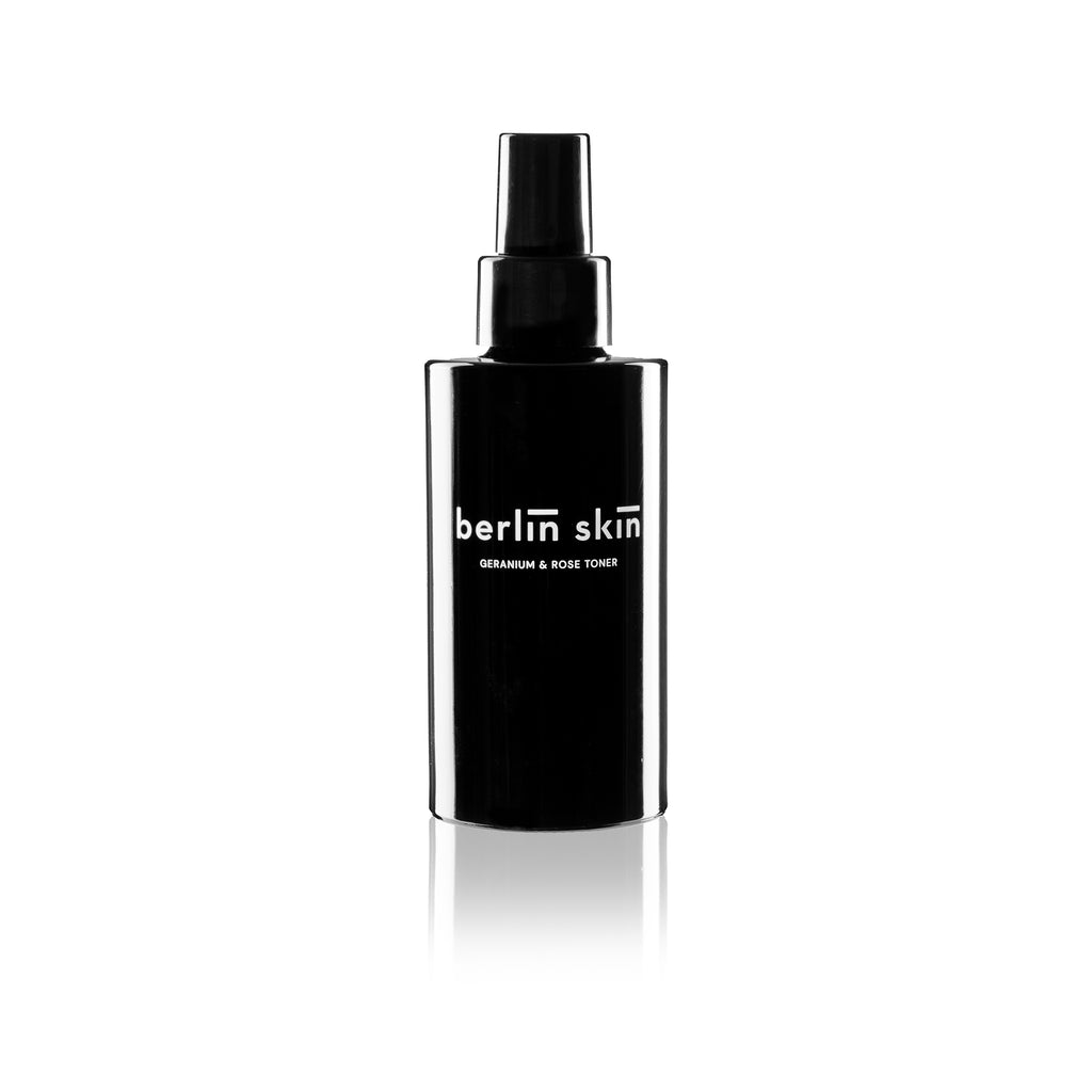 Black bottle of berlin skin geranium & rose toner with a spray nozzle, isolated on a white background.