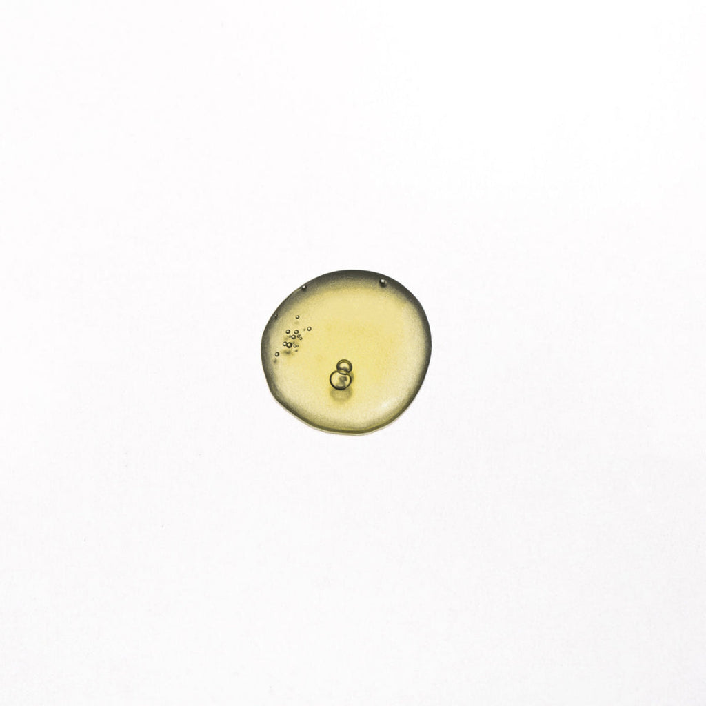 A small drop of yellow liquid with bubbles isolated on a white background.