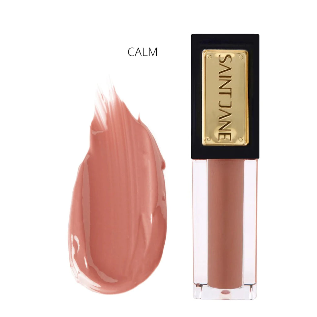A swatch of beige lipstick color named "calm" next to its tube with a black cap and gold label.