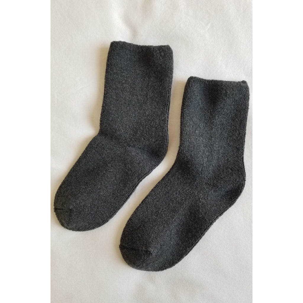 A pair of grey socks laid out flat on a white surface.