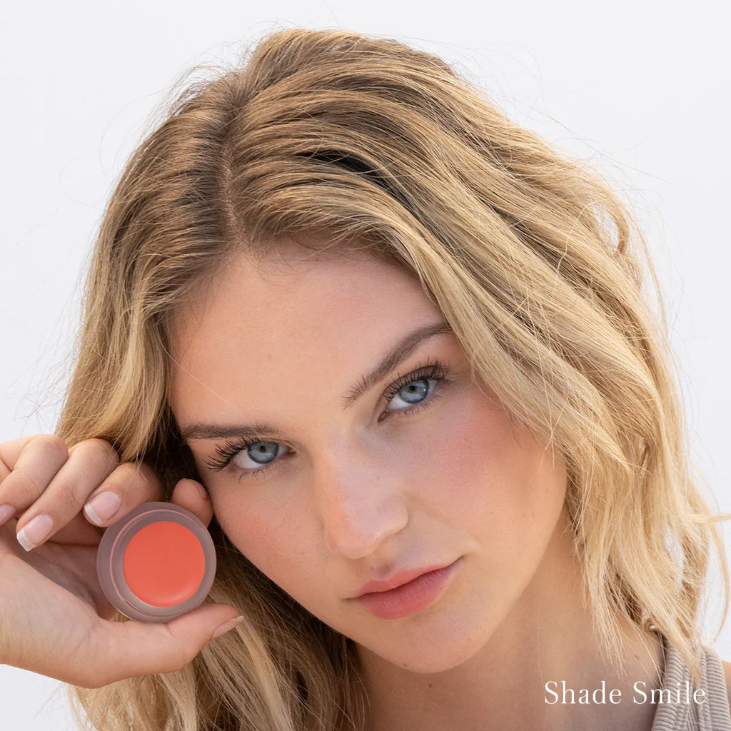 Woman holding a cosmetic product near her face with text "shade smile" indicating the color of the product.