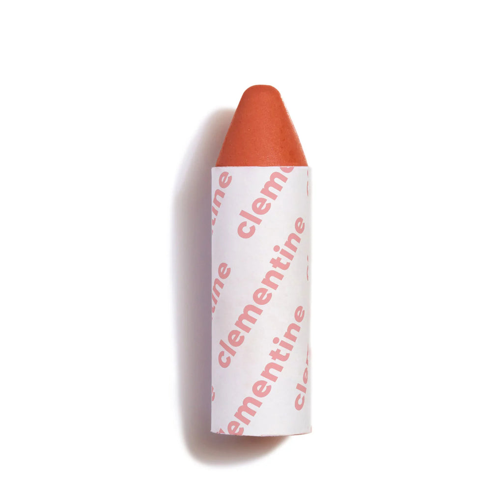 A single orange lipstick with its cap on against a white background.