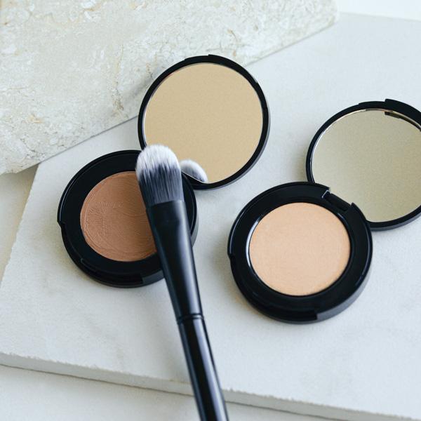 Cosmetic powders in compacts with a makeup brush.
