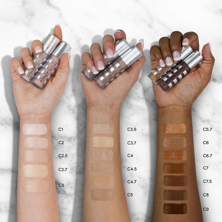 Three sets of hands displaying foundation swatches for different skin tones on a marble background.