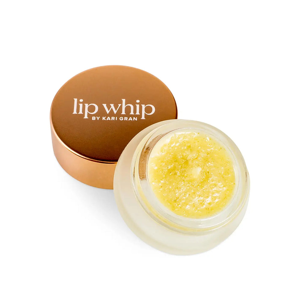 A jar of lip whip next to its copper-toned lid against a white background.