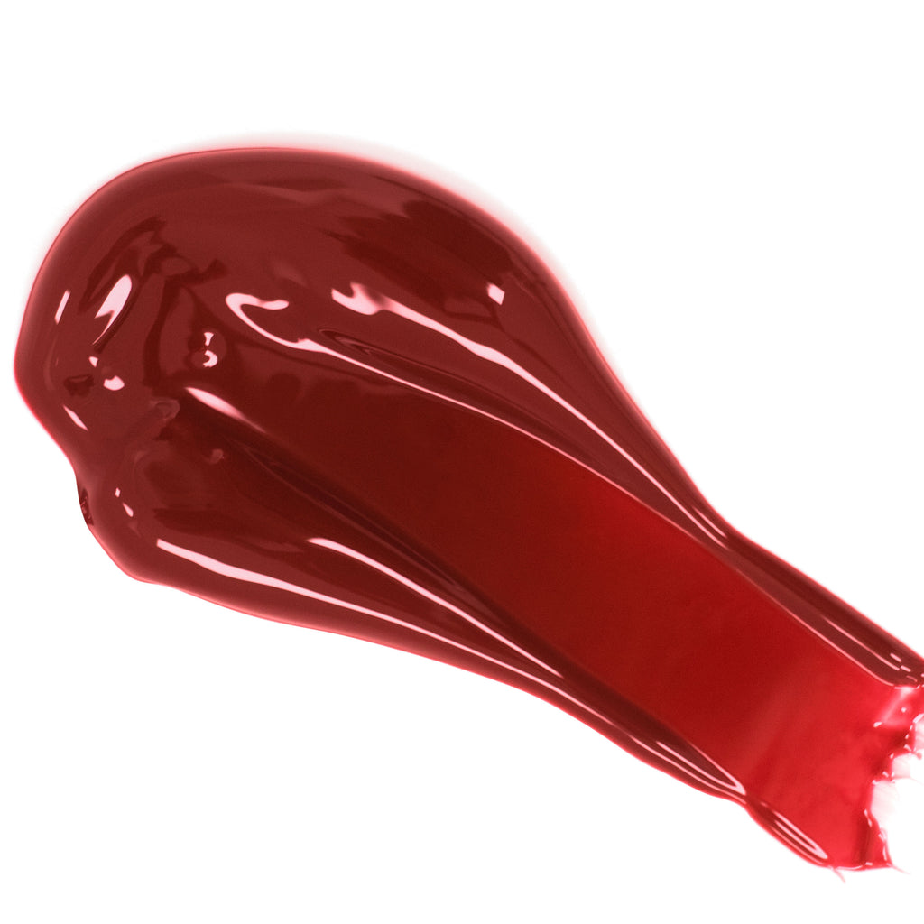 A smear of glossy red lipstick on a white background.