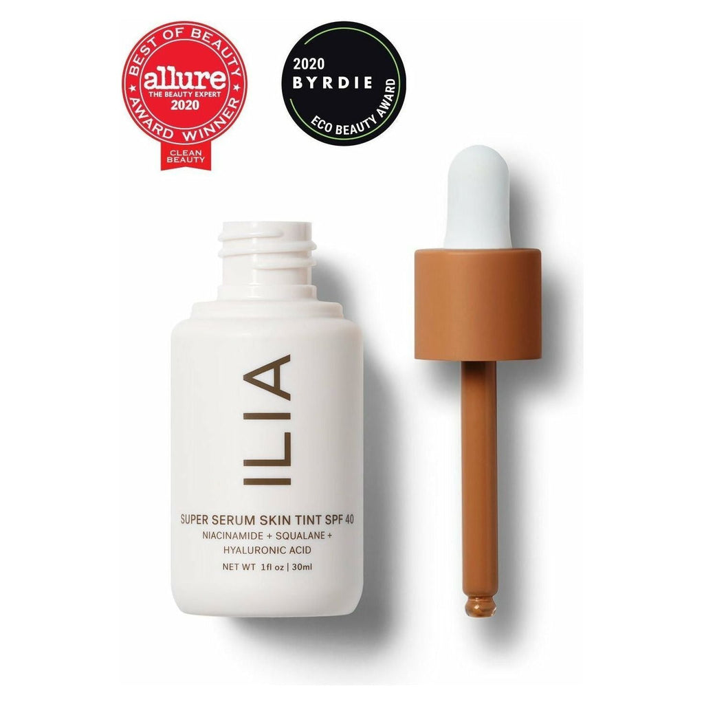 A bottle of ilia super serum skin tint spf 40 alongside its dropper, displaying beauty awards from allure and byrdie for 2020.