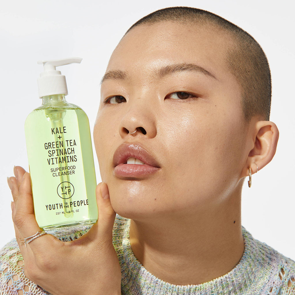 Woman holding a bottle of kale and green tea facial cleanser.