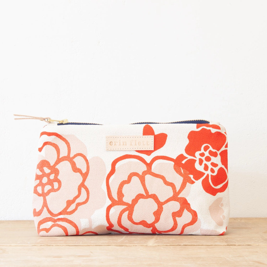 Floral-patterned fabric pouch on a wooden surface against a white background.