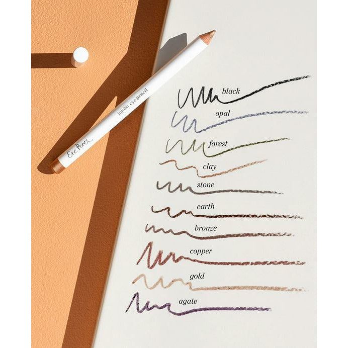 A set of color swatches in earthy tones with their names, alongside a pencil on a notebook.