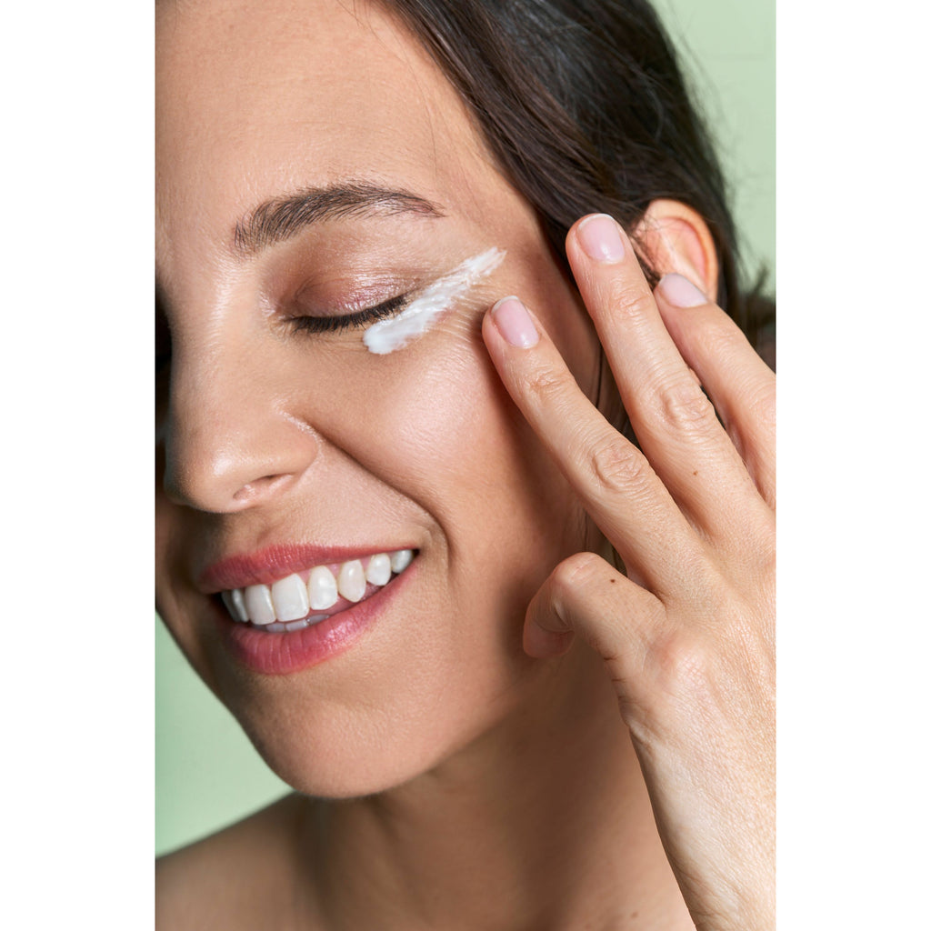 Woman applying facial cream around her eye area.