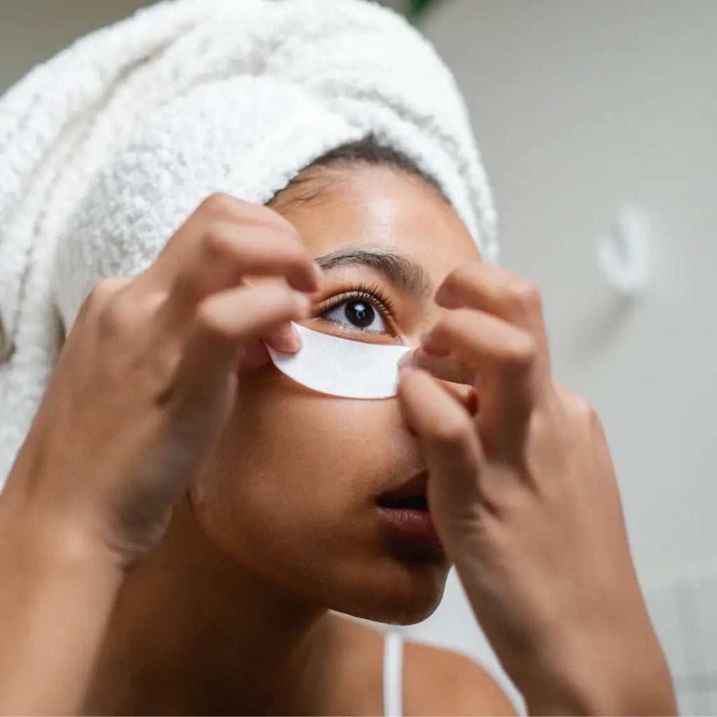 Woman applying a facial treatment patch under her eye.