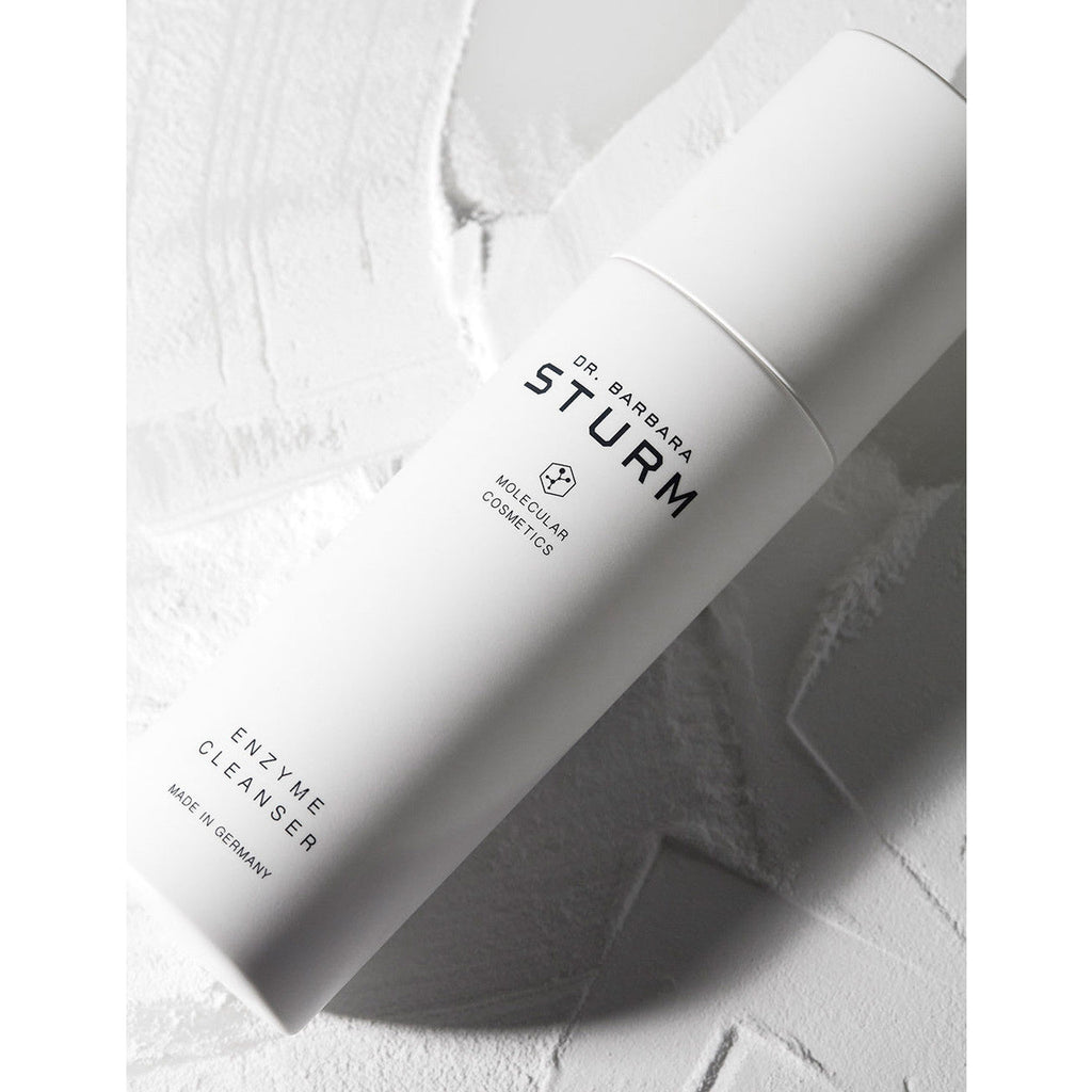 White skincare product bottle with label "dr. barbara sturm enzyme cleanser" on a textured white background.