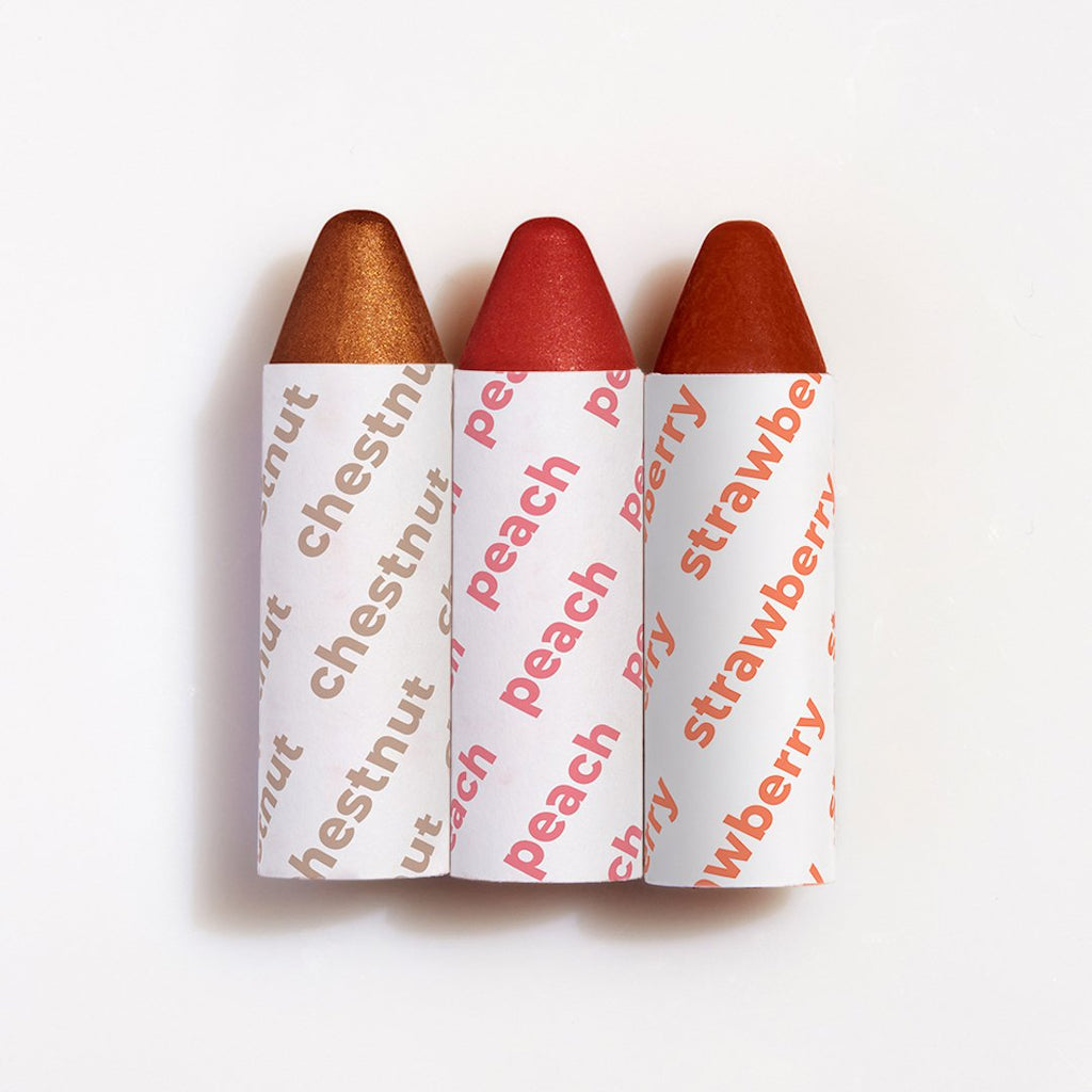 Three teardrop-shaped lipsticks with shades of brown, red, and burgundy, partially wrapped in labeled paper.