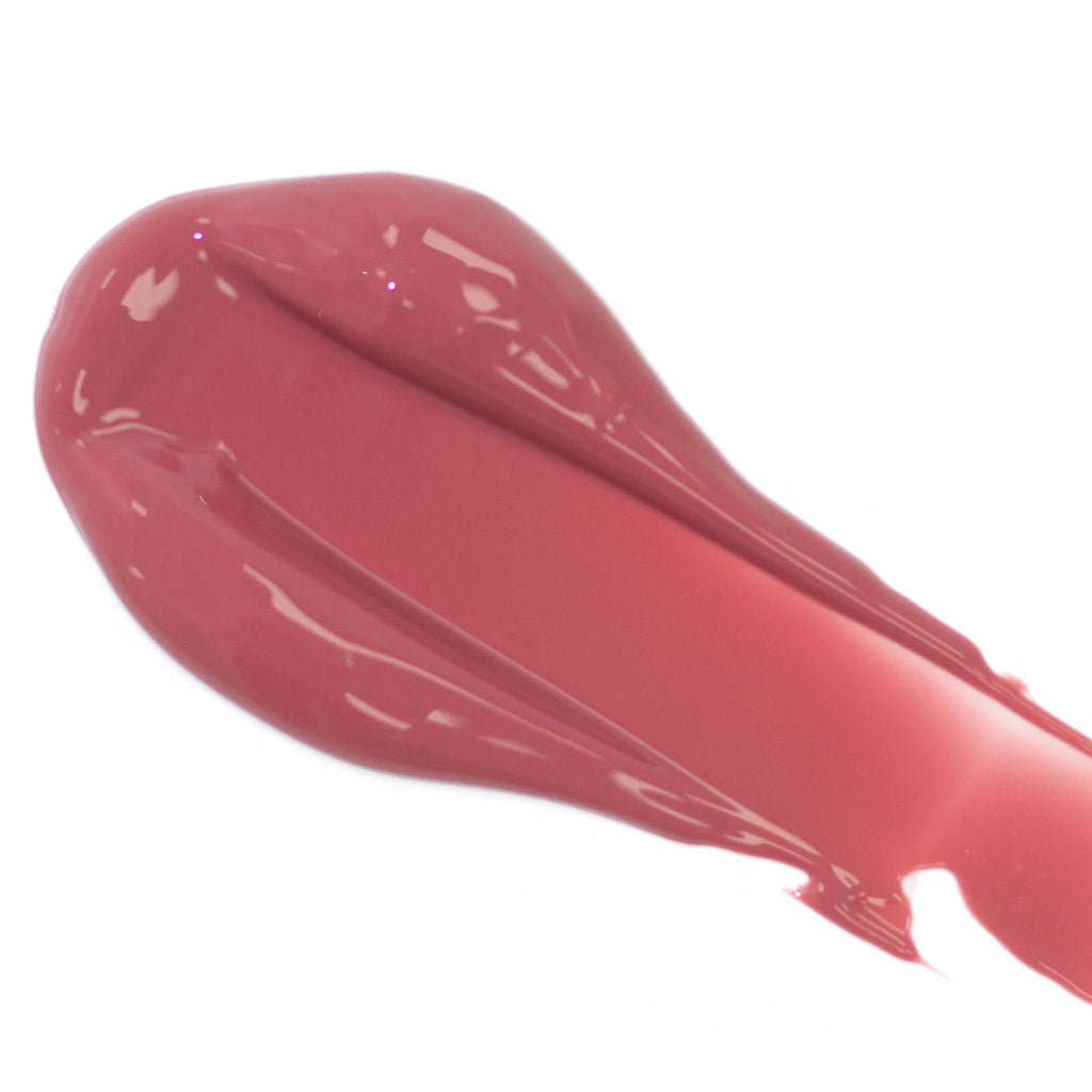 A smear of glossy pink lipstick on a white background.
