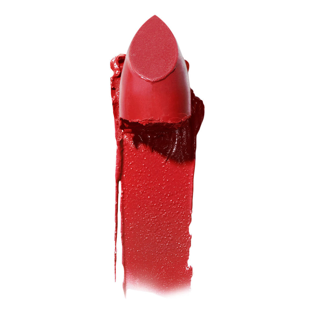 A close-up of a broken red lipstick with smudged texture on a white background.
