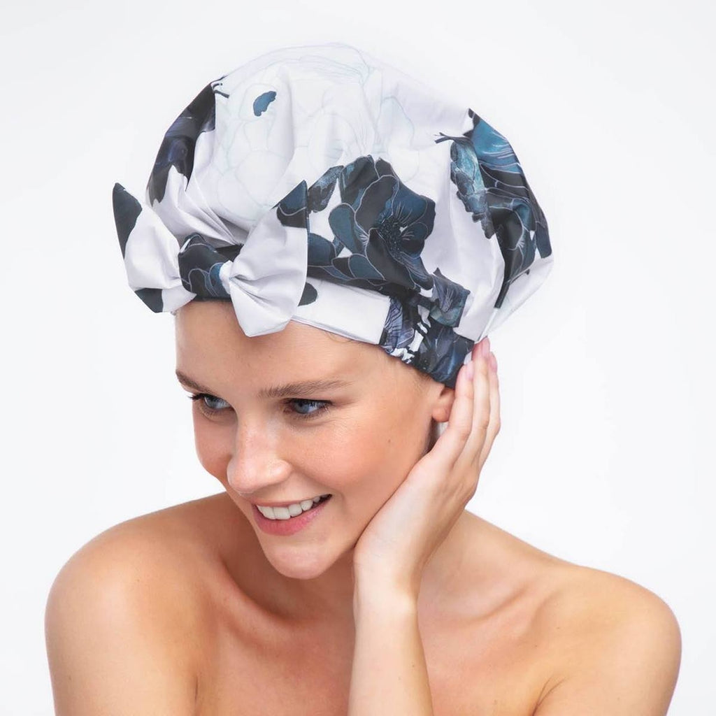 A woman wearing a floral patterned headwrap smiles against a white background.