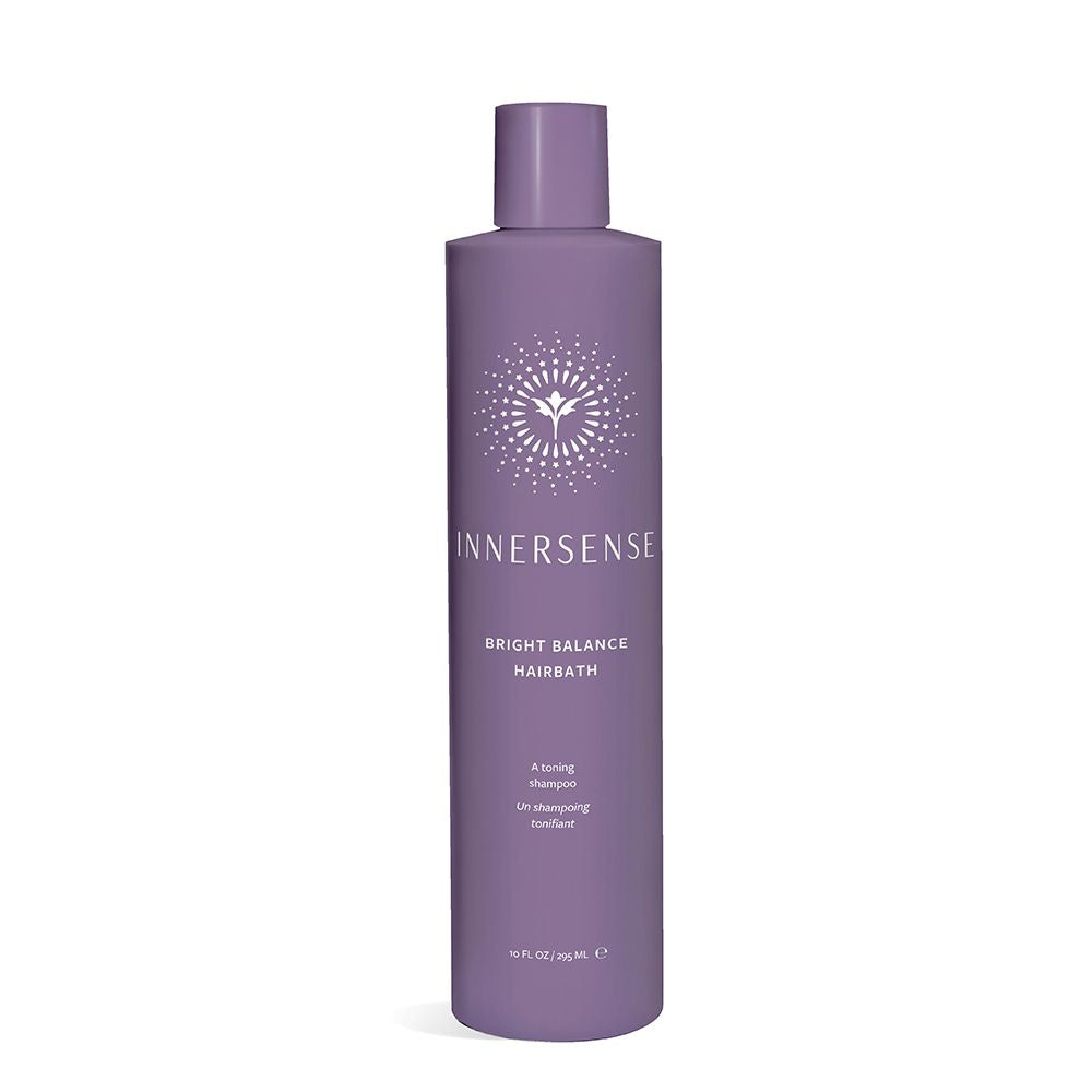 A bottle of innersense bright balance hairbath shampoo against a plain background.