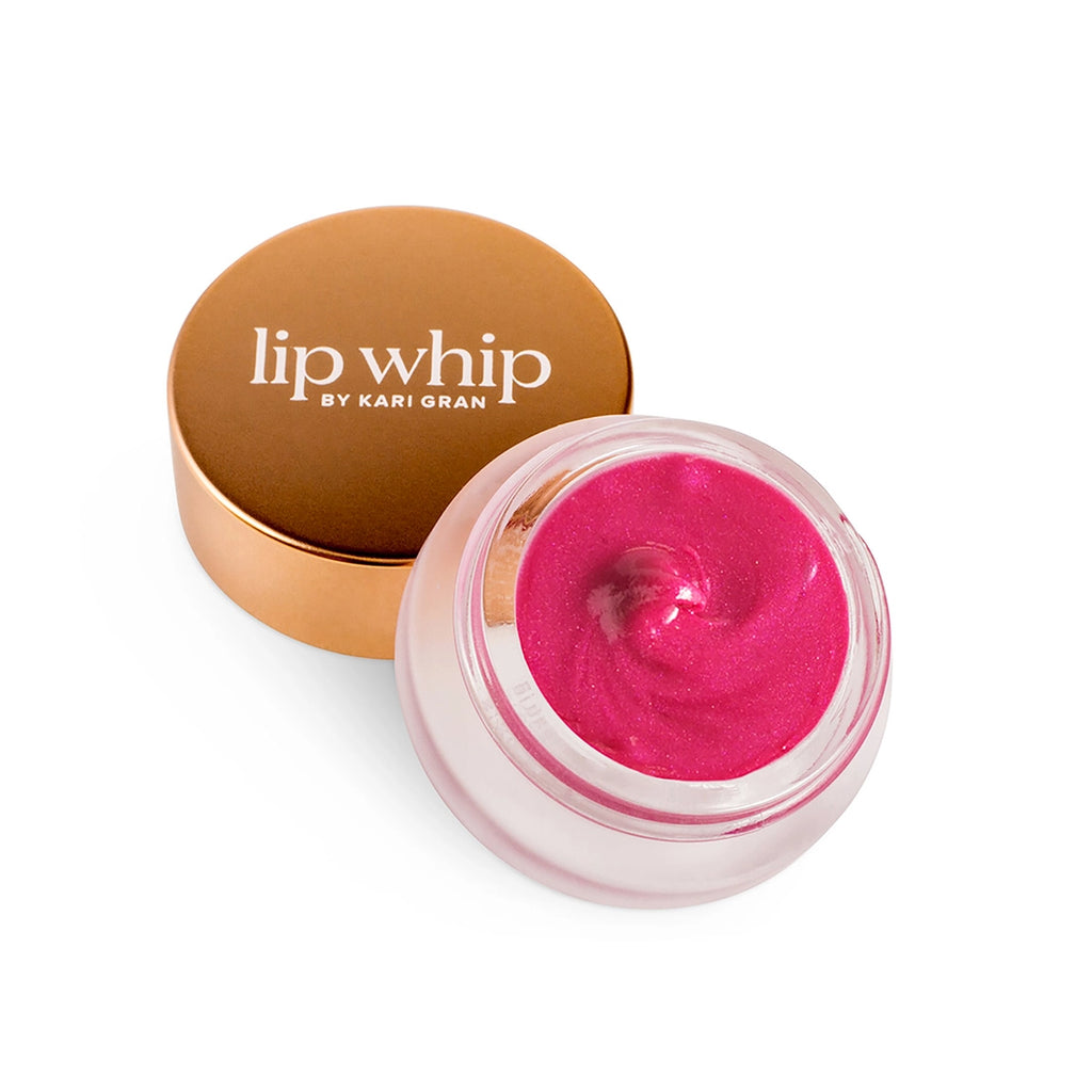 Open jar of pink lip balm next to its copper-colored cap on a white background.