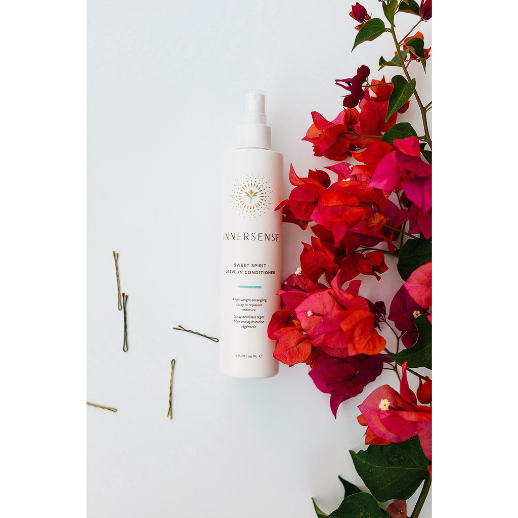 Bottle of innersense organic hair conditioner with vibrant bougainvillea flowers against a white background.