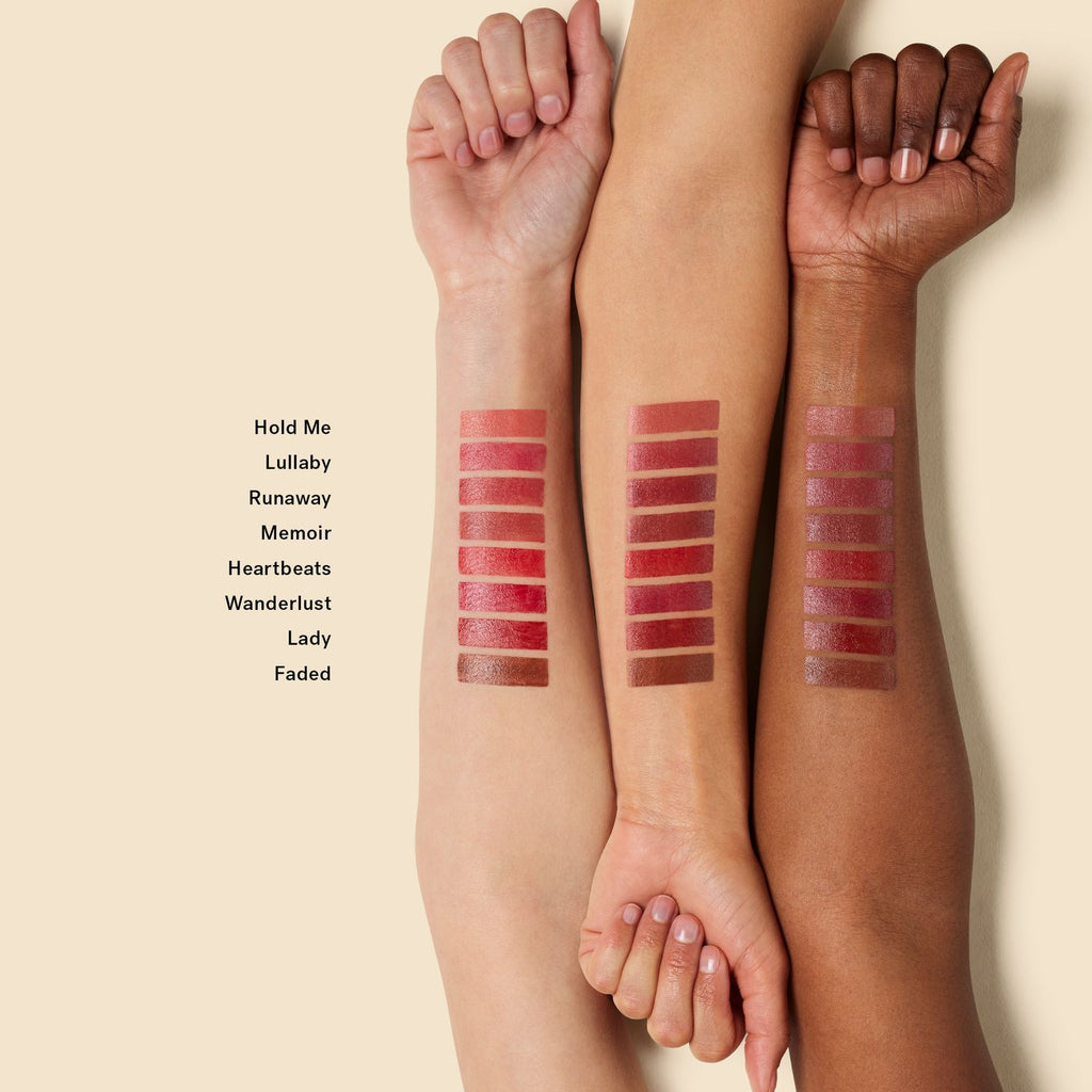 A range of lipstick shades swatched on three arms with different skin tones to demonstrate color variation.