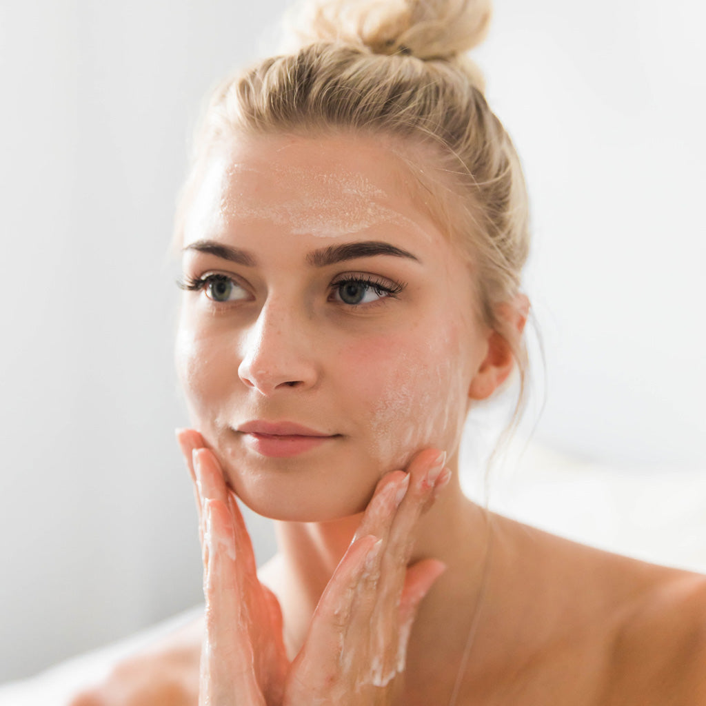 A woman applying facial cleanser to her skin.