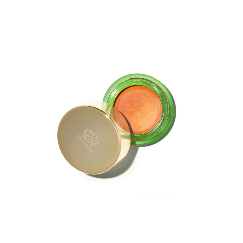 Open compact with green lid containing orange-hued blush on a white background.