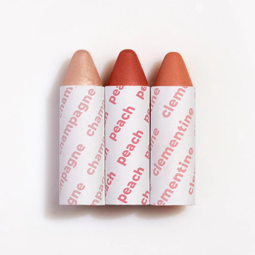 Three lipsticks with shades named champagne, peach, and clementine, arranged in a row against a white background.