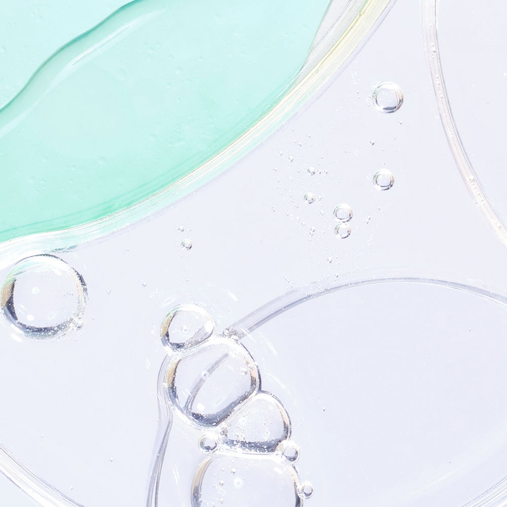 Pale turquoise and clear liquid bubbles on a smooth surface.