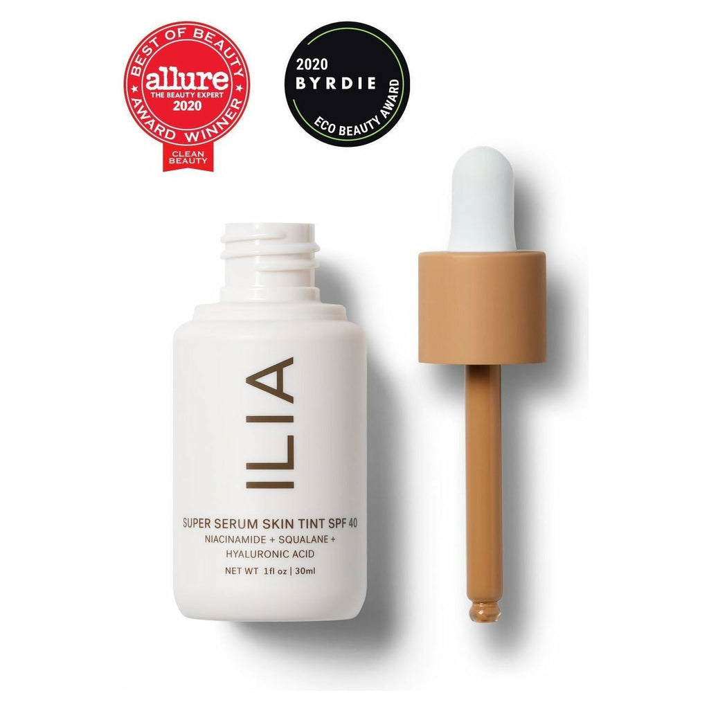 A bottle of ilia super serum skin tint spf 40 with its dropper, featuring beauty award badges from allure and byrdie for 2020.