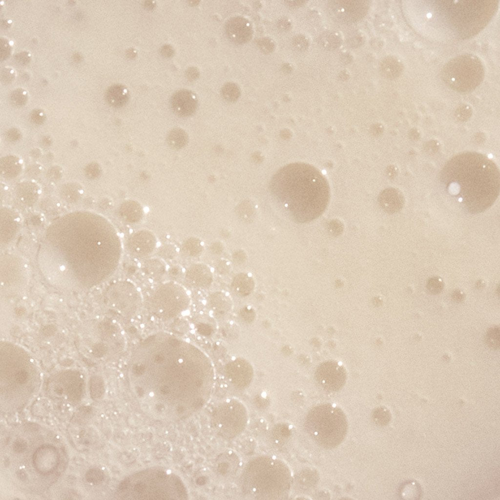 Close-up of bubbles in a beige liquid, possibly a frothy beverage or a chemical solution.