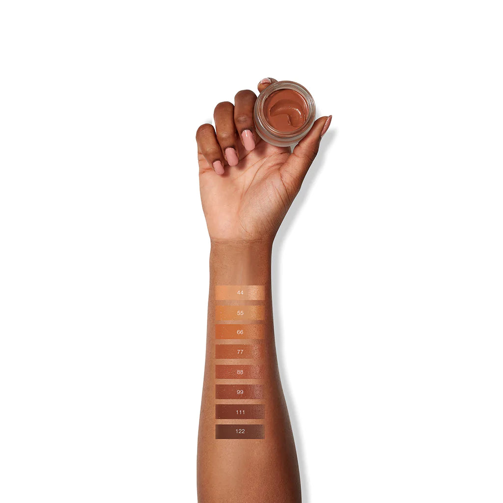 Swatches of various shades of foundation makeup on a person's arm, showcasing a range of colors for skin tone matching.