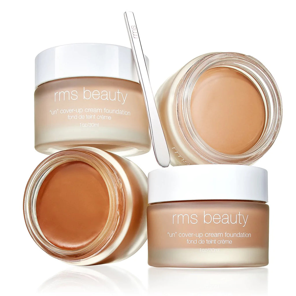 A collection of rms beauty cream foundation containers with one container open, showing the product inside.