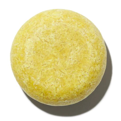 A single round yellow bath bomb on a white background.