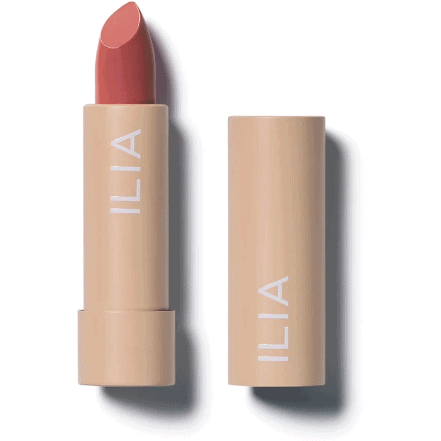 A tube of ilia brand lipstick partially extended next to its cap.