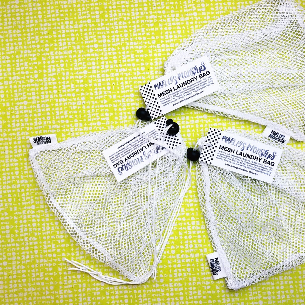 Three mesh laundry bags with tags on a yellow patterned background.