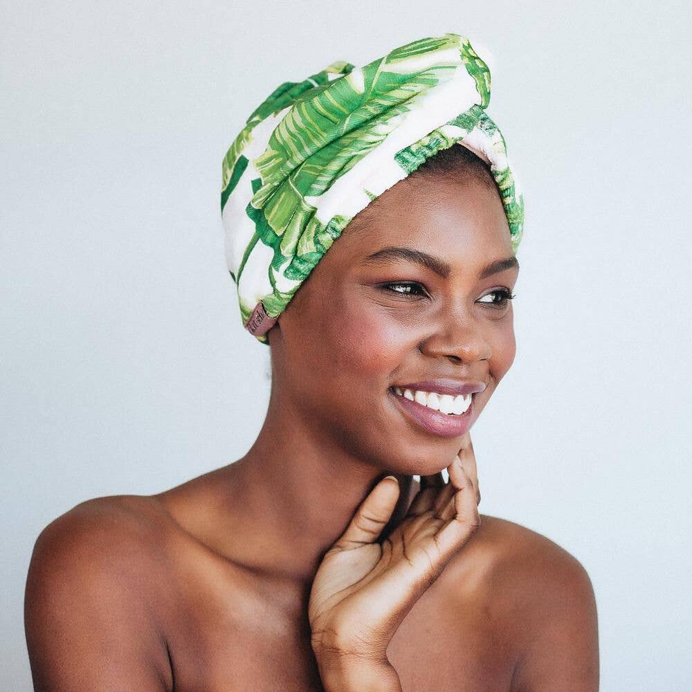 A smiling woman wearing a green and white headwrap.