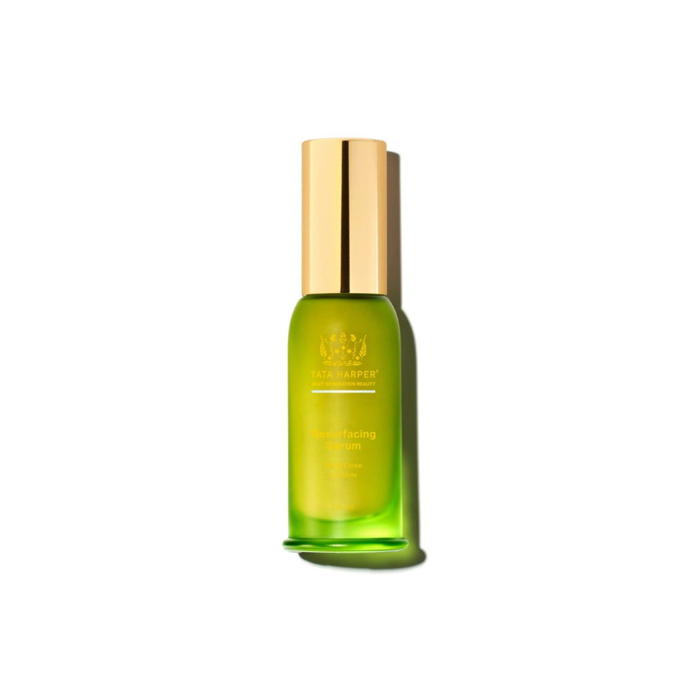 Green glass bottle of tata harper resurfacing serum with a gold cap, isolated on a white background.