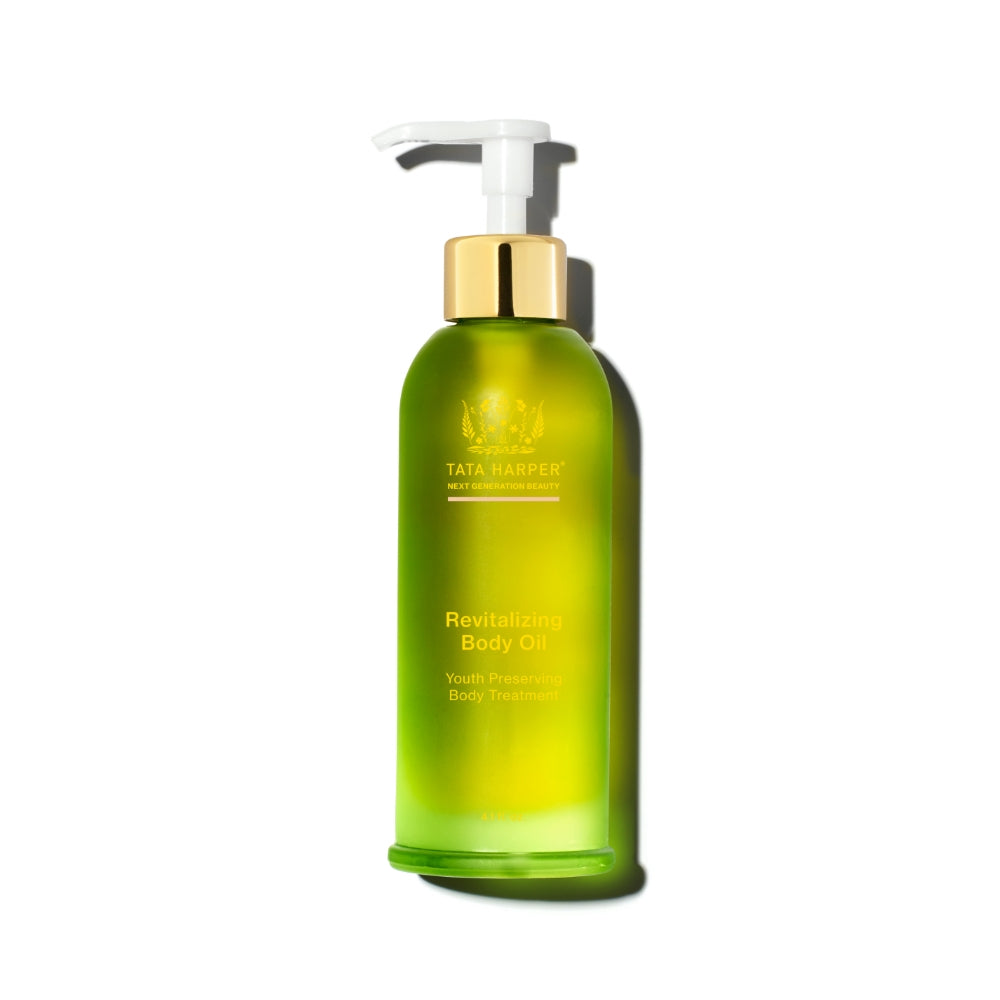Green bottle of tata harper body oil with a pump dispenser against a white background.