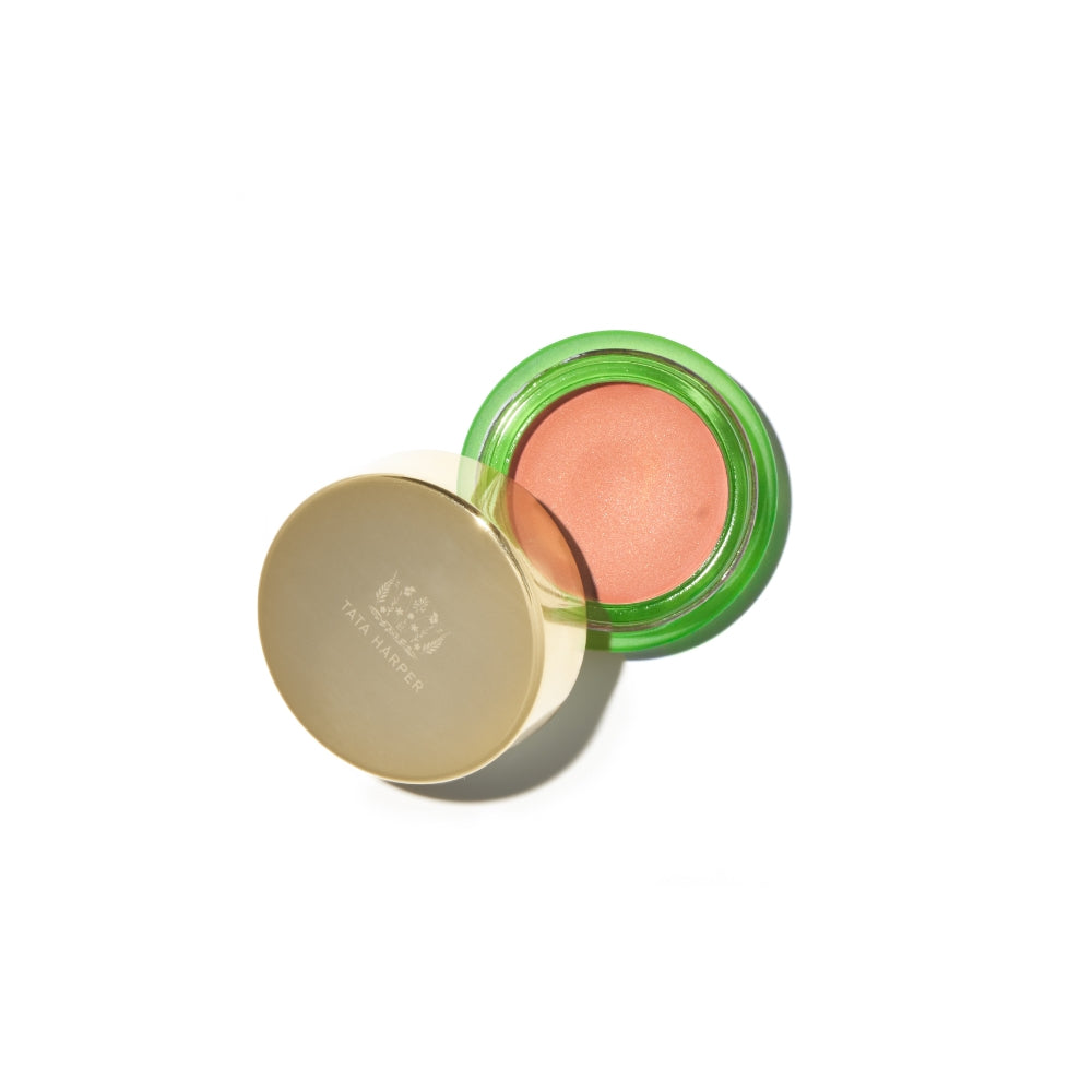 Open container of blush cosmetics with a green lid and gold base, isolated on a white background.