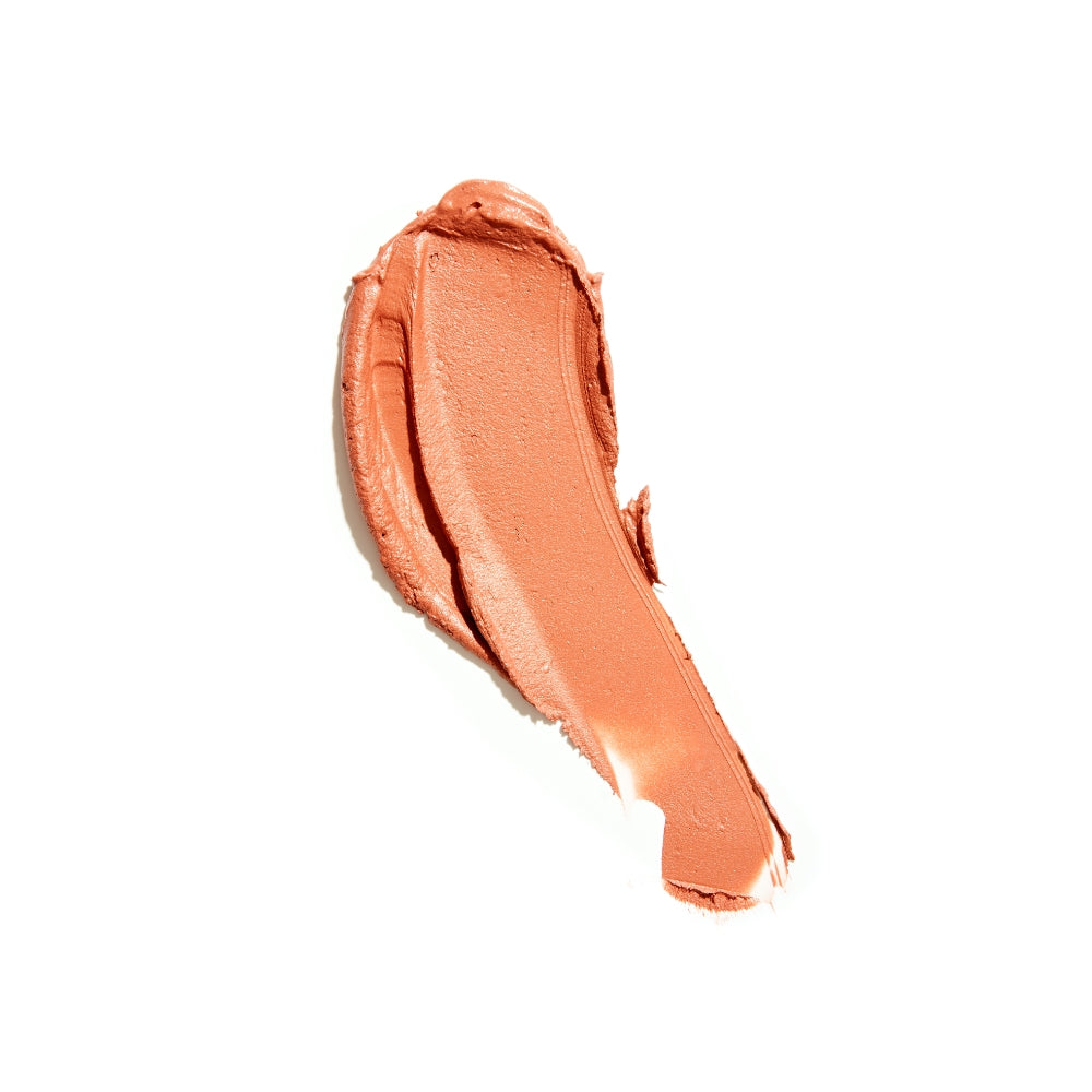 A smear of creamy, peach-colored lipstick isolated on a white background.