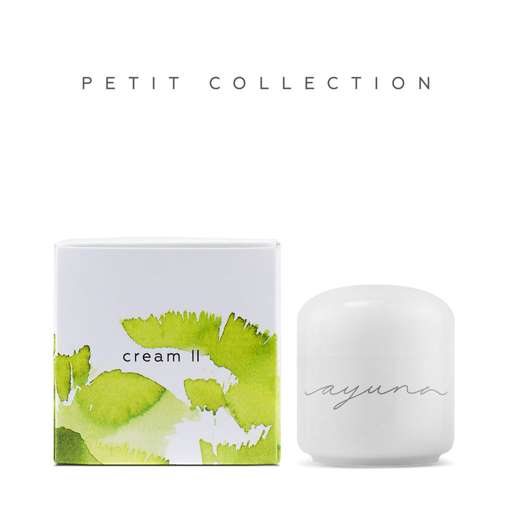 A white cosmetic jar next to its packaging box with a green leaf design and the words "petit collection cream" written on it.
