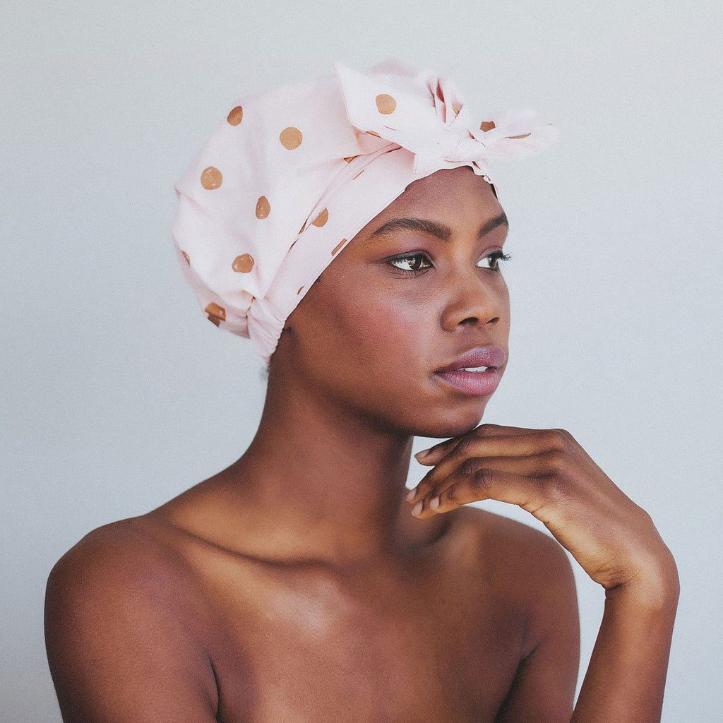 Woman with a polka-dotted headscarf looking thoughtfully to the side.