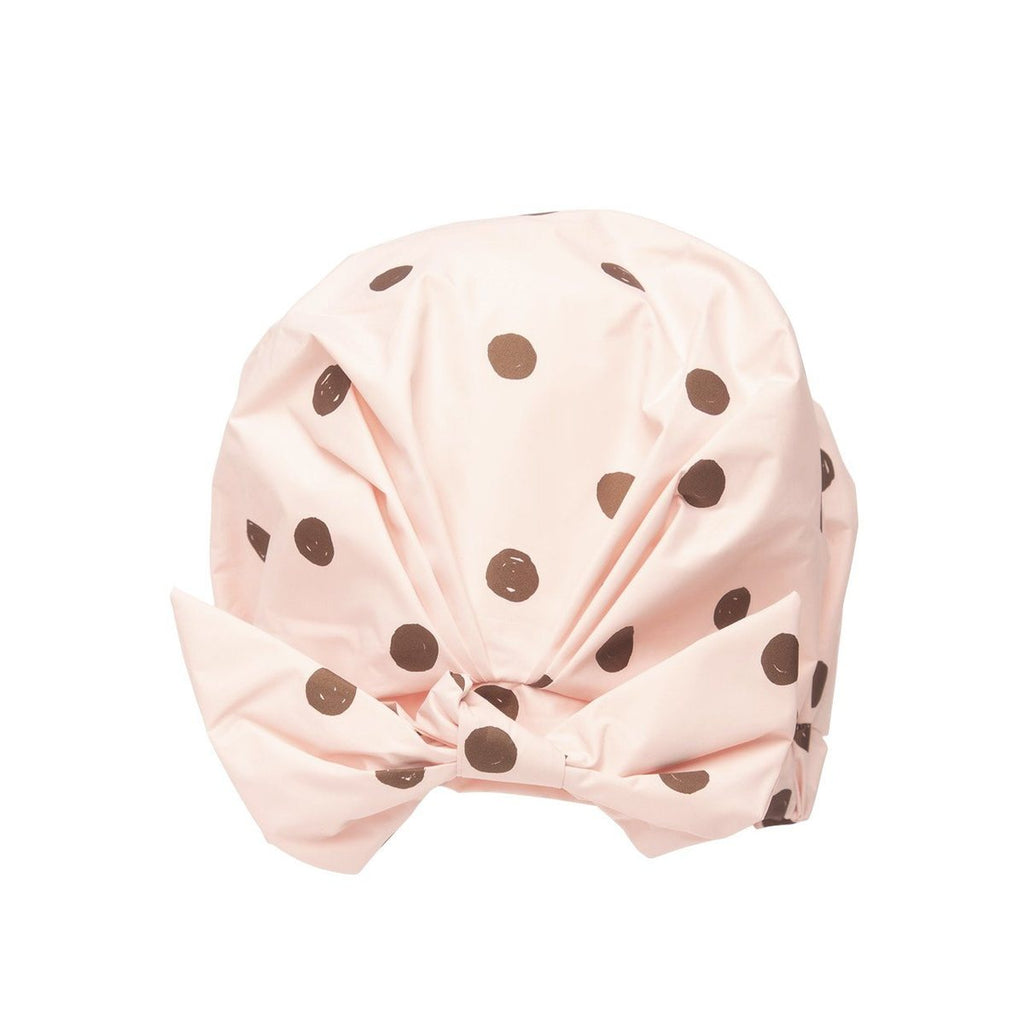 Pink shower cap with brown polka dots and a bow design, isolated on a white background.