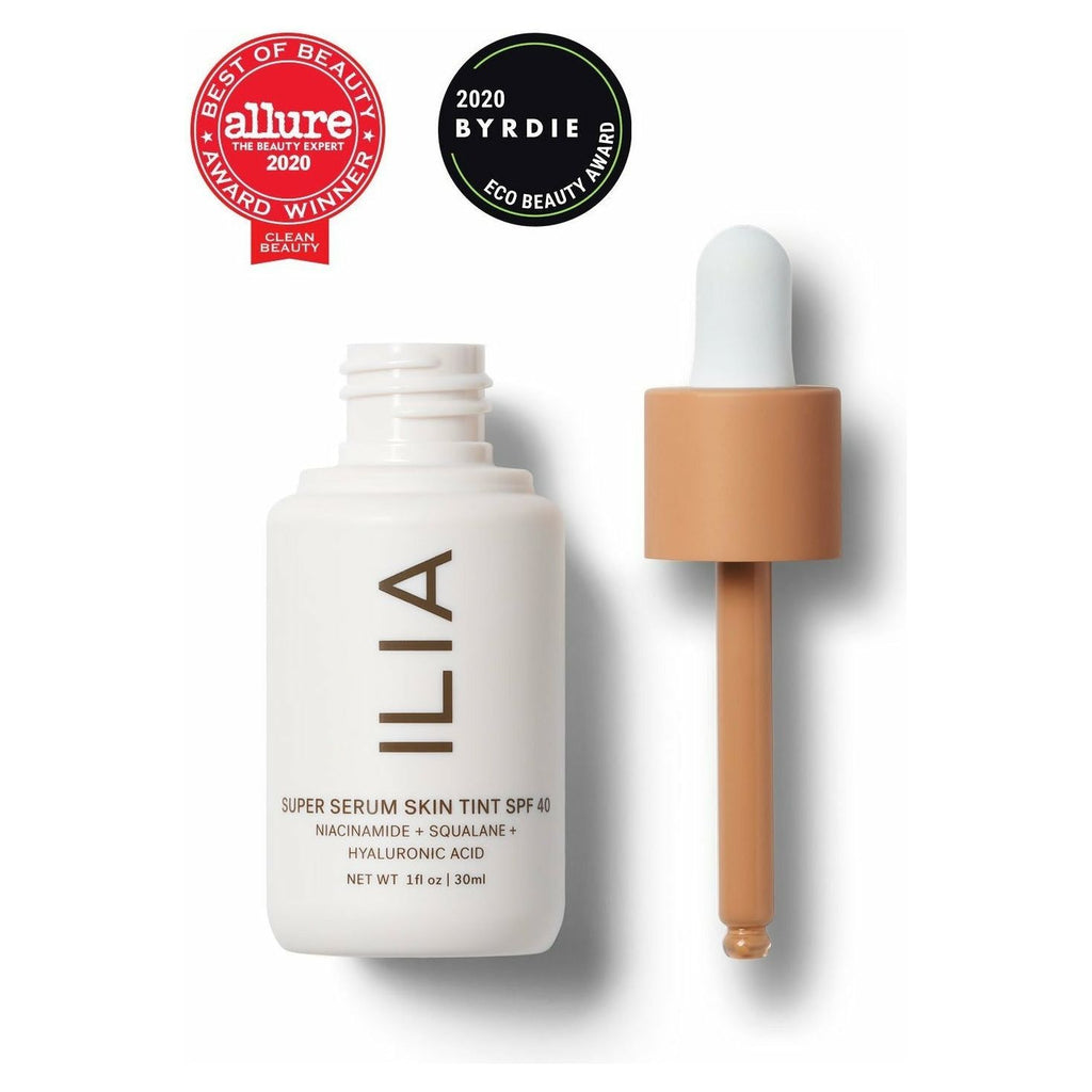 A bottle of ilia super serum skin tint spf 40 with a dropper applicator, awards badges for allure best of beauty and byrdie eco beauty 2020.
