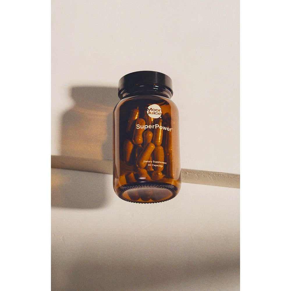 A bottle of "superpower" capsules suspended against a neutral background.