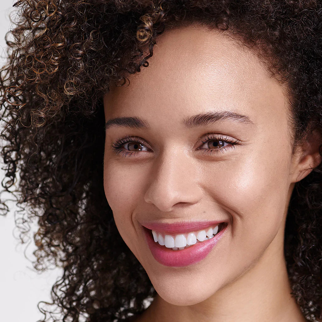 A smiling woman with curly hair against a light background.
